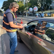 Foto colorida horizontal mostra agente da Balada Segura entregando materiais educativos para motoristas