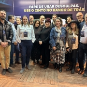 Foto horizontal colorida mostra homens e mulheres posando para a foto no estande do DetranRS na Expointer