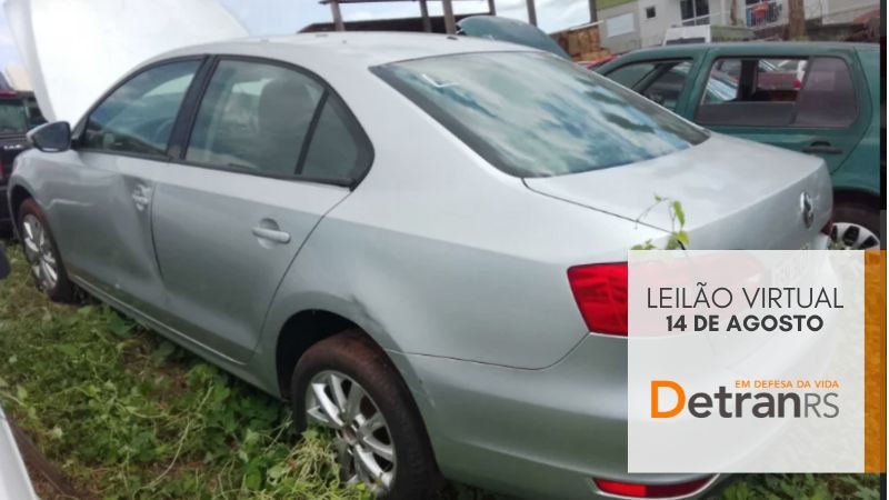 Corolla prateado de lado/costas estacionado em depósito ao lado de outro veículo verde