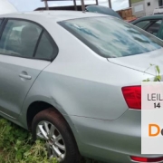 Corolla prateado de lado/costas estacionado em depósito ao lado de outro veículo verde