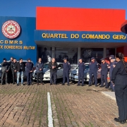 Foto horizontal colorida em frente ao Quartel do Comando-Geral mostra grupo de pessoas, metade delas uniformizada, em frente aos carros doados.