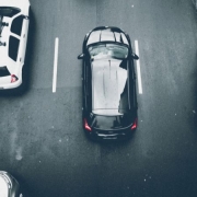 Foto horizontal colorida mostra carros em uma faixa de três pistas vistos de cima