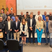 Foto horizontal colorida mostra grupo de formandos posando para a foto em um ambiente de auditório