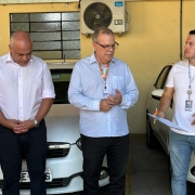 Tres homens em frente a carros brancos